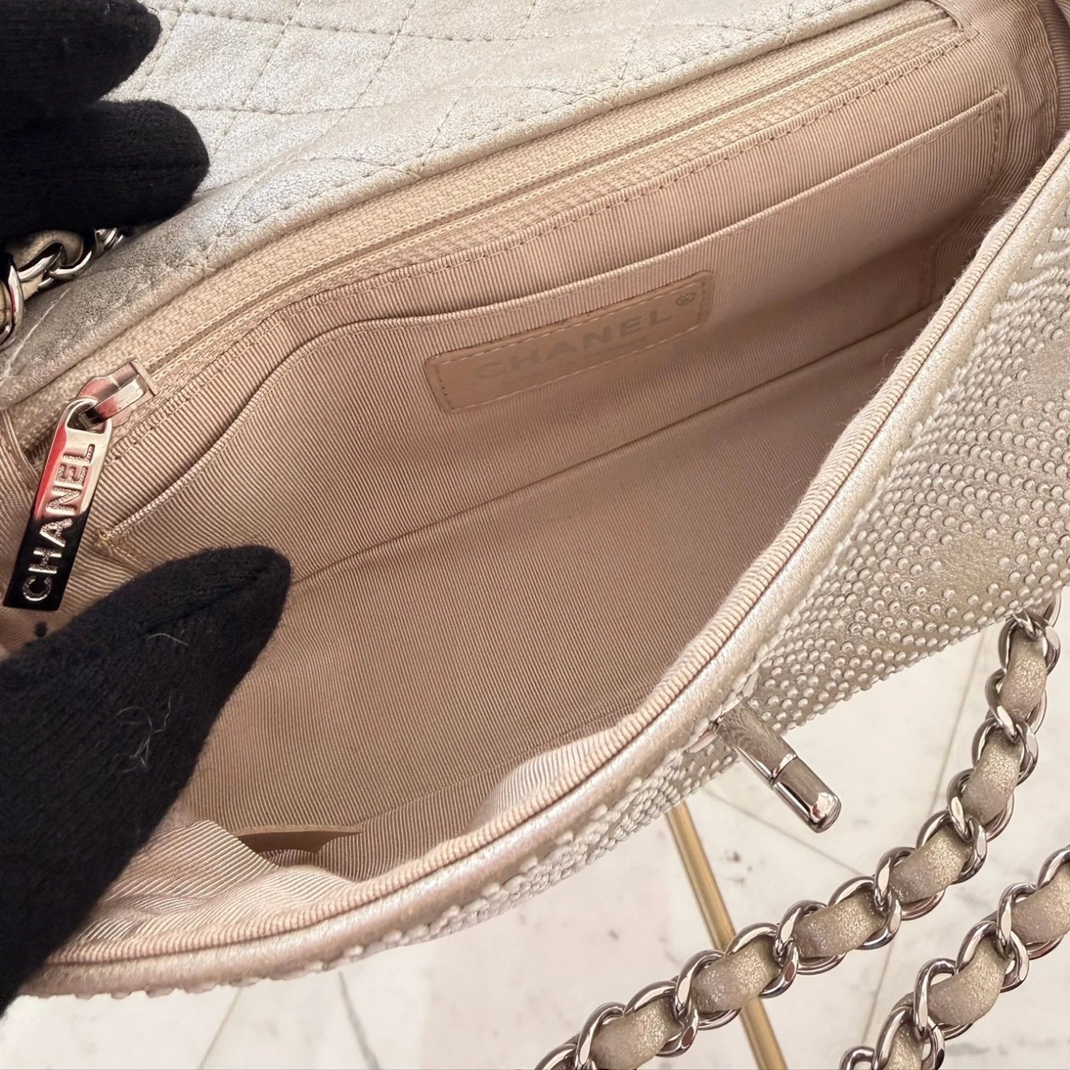 Zip pocket and slip pocket of a Chanel iridescent studded calfskin Mini Flap crossbody bag, with a chain strap and silver hardware available in Cyprus at HOUSE of MICY