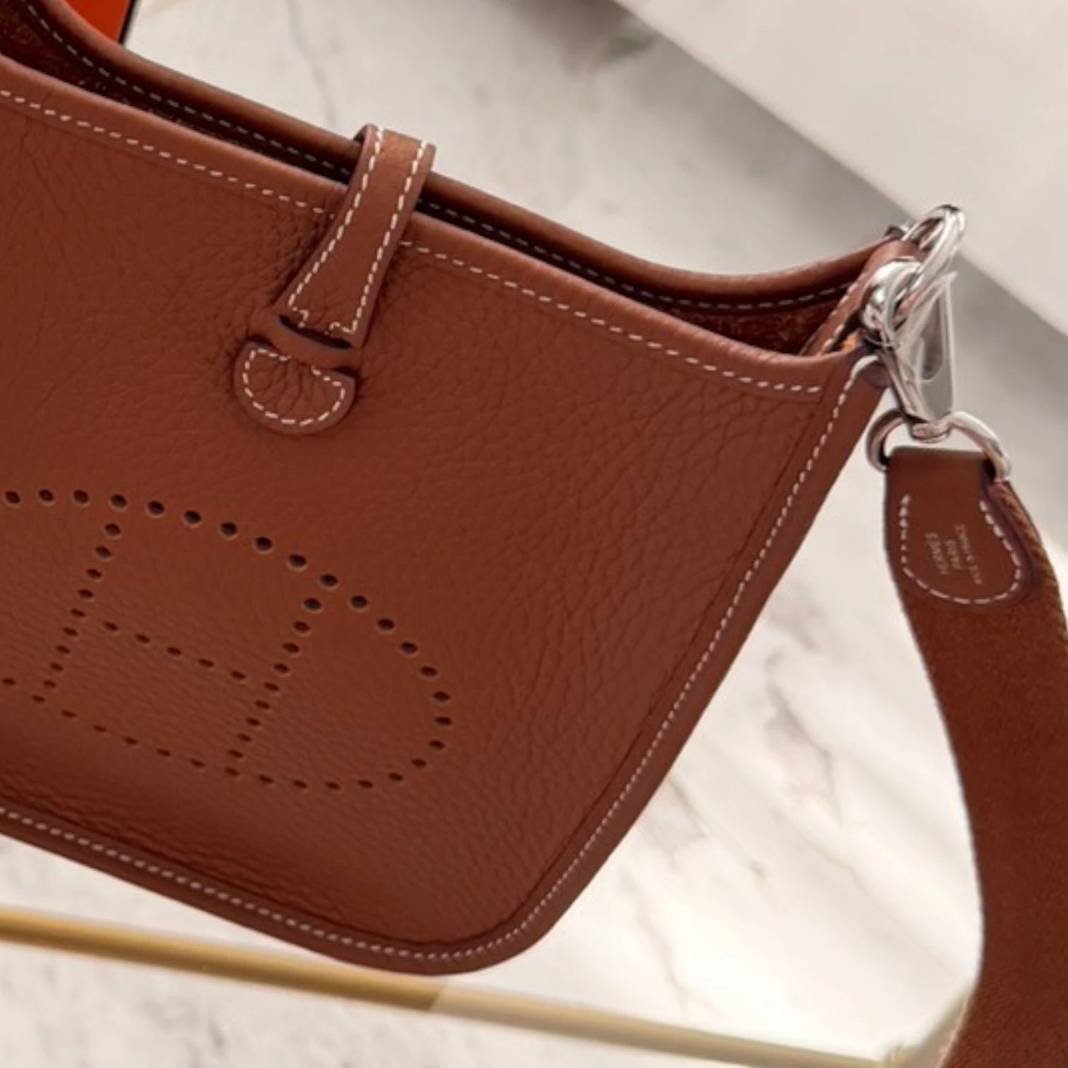 Silver-tone details of a Hermès 2024 Evelyne 16 crossbody bag in Clemence leather, perforated H logo, with a crossbody strap, available in Cyprus at HOUSE of MICY
